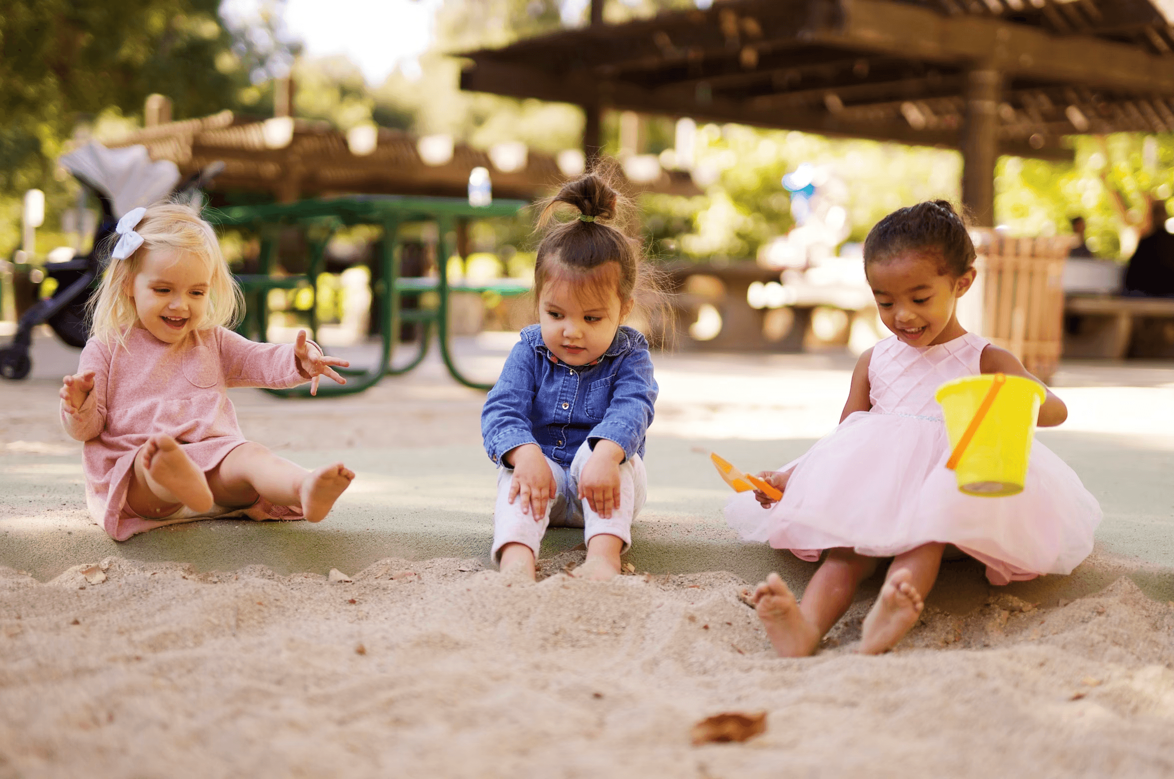 Three happy children playing in sand at Raising Cubs